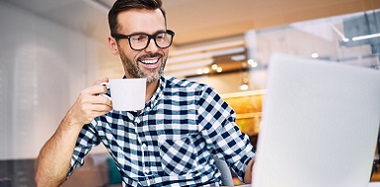 mężczyzna pije kawę przy komputerze