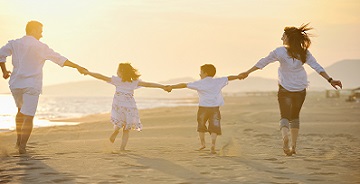 Szczęśliwa rodzina na plaży trzyma się za ręca